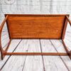 The G Plan Astro Mid Century Modern Vintage Teak Coffee Table from the 1960s is shown upside down on a light-colored wooden floor. The underside of the table's rectangular top is visible, revealing its construction. The table legs extend upward, highlighting their curved design. A decorative logo can be seen on the wall in the background.