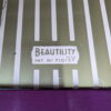 Close-up image showing a logo that reads "Beautility REGD. PAT. NO. 710157" on a surface with a pattern of vertical white and beige stripes. The bottom part of the image includes a section with a solid purple color, presumably indicating the Mid Century Beautility Drinks Cabinet, Vintage 1960's Walnut Cocktail Bar.