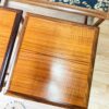 A close-up of the G Plan Astro Long John Teak Nest Of Tables alongside a matching wooden stool. The table features a sleek black surface adorned with a decorative edge pattern. The floor is light-colored hardwood, and in the bottom left corner, there is a logo with the tagline "Flip It & Restore It".