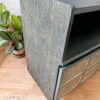 A close-up view of a refurbished Green and Gold Painted MCM Nathan Cabinet/Media Unit/Entertainment Sideboard, featuring textured sides and drawer fronts. It sits on a wooden floor with a potted plant next to it, and the floor displays the logo "Flip It & Restore It.