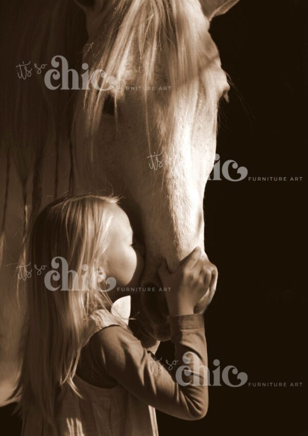 A sepia-toned image titled "Spotty Dog" from the It's So Chic Furniture Art collection features a young girl with long blond hair gently holding and kissing the muzzle of a white horse. The horse's head is lowered, and both appear calm and affectionate. The dark background highlights the serene moment between the two subjects. Overlaid on the image are the words "It’s So Chic Furniture Art.