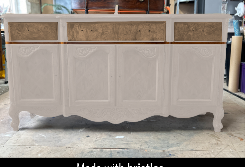 A vintage wooden dresser in the process of being painted sits in a workshop. The top drawers have been removed, while the rest is partially painted white, revealing intricate carvings on the lower sections. The text "Made with bristles" is displayed at the bottom.